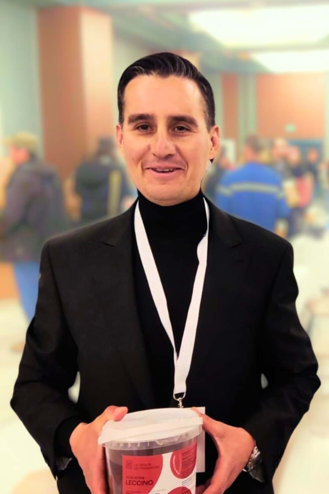 antonello ciccocioppo titolare della tenuta dei trabocchi imbraccia un vaso di olive leccino da tavola della tenuta dei trabocchi durante una fiera in abito elegante